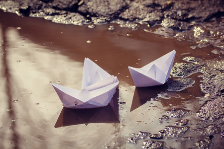 The paper boat floats through the spring puddles. Children's entertainment. Paper origamiの写真素材