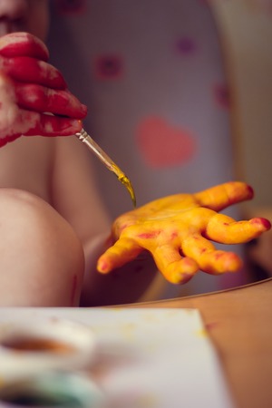 The boy paints on paper. Red and yellow paint. Children's activities. Children's hobby. Drawing