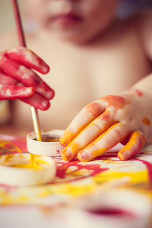 The boy paints on paper. Red and yellow paint. Children's activities. Children's hobby. Drawingの写真素材