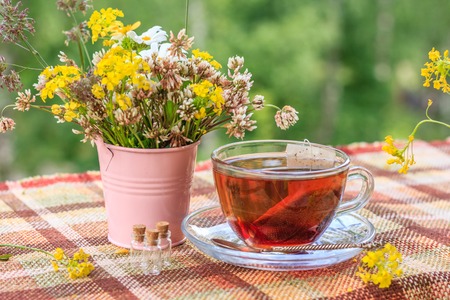 Summer tea with a book on the terrace. Summer tea with a bouquet of flowers. Cup with tea, flowers, book, balconyの写真素材