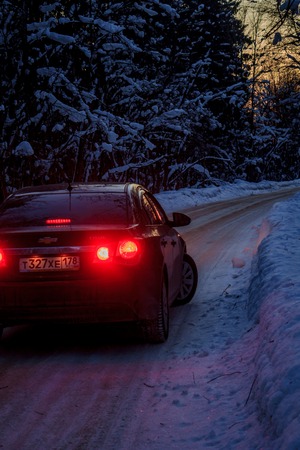 Car on the winter road in the evening. Night road. Road outside the city. Black car Car out of town in the winter. Russia, Leningrad region, March 1, 2018のeditorial素材
