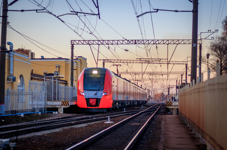 The train swallow rides on the Russian railway at sunset. Russia, Leningrad region, Gatchina, April 11, 2018のeditorial素材