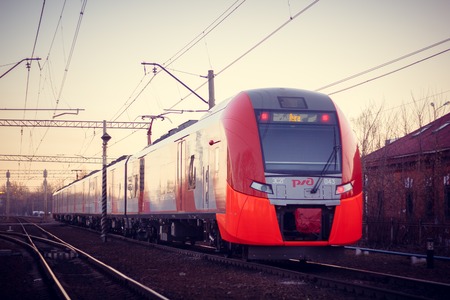 The train swallow rides on the Russian railway at sunset. Russia, Leningrad region, Gatchina, April 11, 2018のeditorial素材