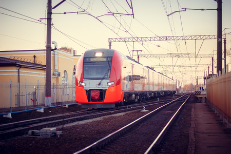 The train swallow rides on the Russian railway at sunset. Russia, Leningrad region, Gatchina, April 11, 2018のeditorial素材