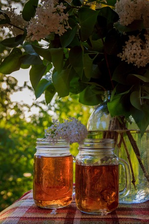 Cold drink tea black in glasses. Tea on the balcony. Tea for Two. Cold drink. Bouquet of flowers . Flowers and teaの写真素材