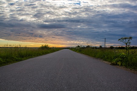 Road in the field at sunset. Summer field. Asphalt road. Summer landscape. Russian roads. Expanses of Russiaの写真素材