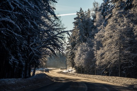 The road in the winter forest. Snow picture. Branches of trees in the snow hang over the road. Beautiful winterの写真素材