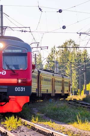 Russian train in the summer. The train rides in the summer at sunset. The train pulls up. Public transport. Russia, Oranienbaum July 31, 2018のeditorial素材