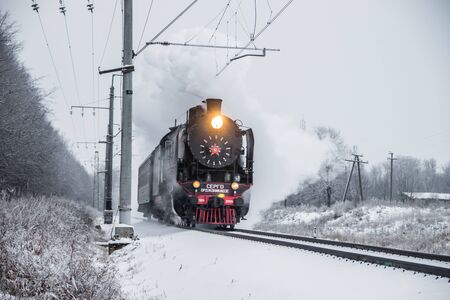Old locomotive rides by rail in winter. Public transport. Passenger transportation. Russian locomotive. Russian railway. Winter road. Russia Leningrad region Gatchina, December 16, 2018のeditorial素材