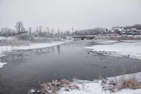 Winter landscape on the river. Snow picture. Snow and river. Cloudy snow day. Freezing dayの写真素材