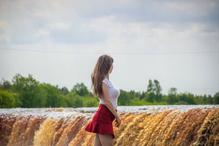 The girl at the waterfall. Young beautiful girl on a little waterfall. Little waterfall.の写真素材