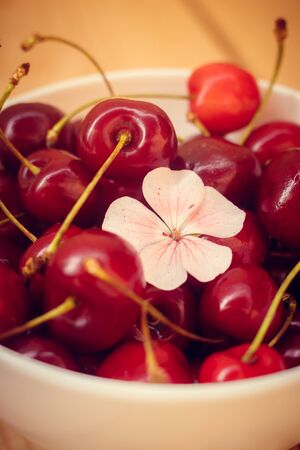 Sweet cherry berries in a white bowl on a woodenの写真素材