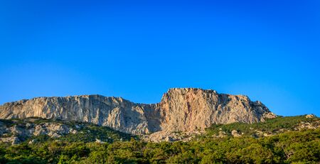Russian mountains. Crimea. Summer mountains background. Forest and mountains in the sun on the background of a cloudy sky above the peninsula of Crimea, Russia. Sunny, bright, saturated raster photoの写真素材