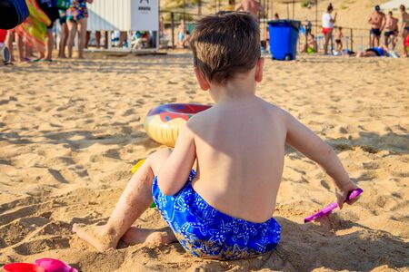 A boy plays a typewriter on the beach. Children's games. Beach in the summer. Small child . Sand beachの写真素材
