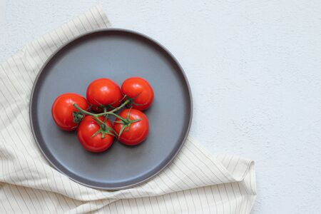Tomatoes on a branch on a plate . Vegetables. Article about healthy food. Red vegetables. Ripe red tomato vine for cooked food on the table.の写真素材