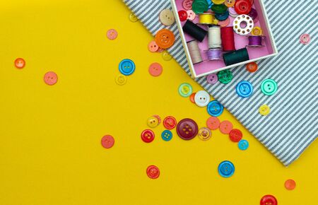 Layout with place for text buttons for clothes. Article about sewing, needlework. Do it yourself. Bright yellow background. Colored buttons.の写真素材