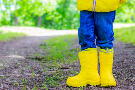 Yellow rubber boots on the child's feet . Shoes for wet weather. Children's shoes. Ads for rubber...