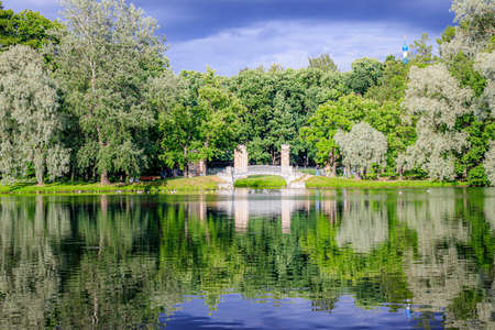 Mirror image in the Park by the water with the bridge. Summer Park. The lake in the Park. City park. Beautiful summer landscape. nature of russiaの写真素材