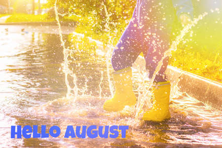 Rubber boots in a puddle. The spray from the water. Summer rain. Photo design with text in English....