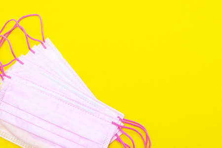 Medical mask isolated on a yellow background. Pink face mask. Article about the second wave of coronavirus. Protection of the respiratory system. Pneumonia and coronavirus. Pandemic.の写真素材