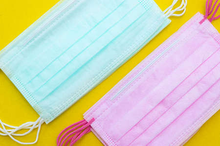 Medical mask isolated on a yellow background. Colored face masks. Article about the second wave of coronavirus. Protection of the respiratory system. Pneumonia and coronavirus. Pandemic. Copy spaceの写真素材