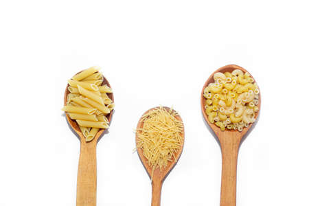 Macaroni several types in wooden spoons on a white background. Macaroni on wooden spoons. Macaroni on a white background.の写真素材