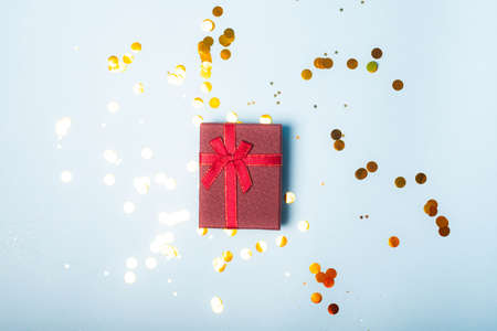 Red confetti gift. Red gift layout on top. Confetti is scattered. New year and Christmas. Valentine's day. Holiday. Article about giftsの写真素材