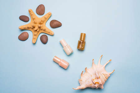 Seashells and flatley nail polish. Delicate nail polish. Nail polish. Women's manicure and pedicure. Beauty. Article about the choice of varnish. Manicure on vacation. Layout of nail polish. Copy space. Blue backgroundの写真素材