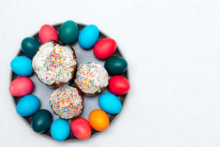 Colored painted eggs and Easter cake on a plate on a white background. Easter. Religious holiday....