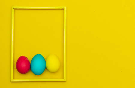 Painted eggs on a yellow background. Chicken eggs on a yellow background in a frame. Space for the...