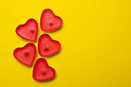 Candles in the form of hearts on a yellow background. Red candles. Red hearts. Yellow background....