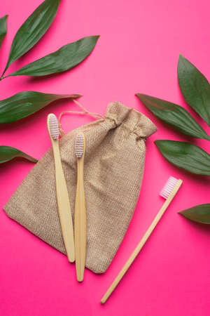 Bamboo toothbrushes and a canvas bag on a pink background. Green leaves. Eco products. No plastic. Health and medicine. Dentistry. Brushing your teeth. Copy space. An article about taking care of the environment.の写真素材
