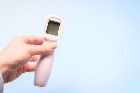 infrared thermometer on a blue background in your hand. the thermometer in his hand. prevention. non-contact temperature measurement. health. human health. check the temperature. copy spaceの写真素材