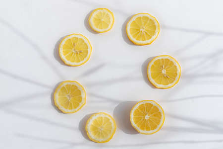 Sliced lemon on a white background. Lemon layout. Sliced fruit. Yellow color. White background. Light and shadow. Citrus. Healthy food. Copy spaceの写真素材