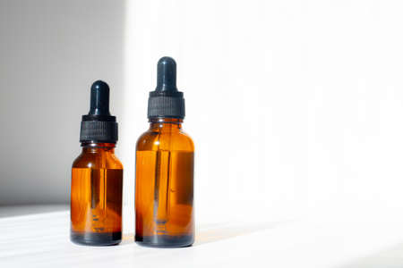 Cosmetic jars with oils on a white background. Light and shadows. Minimalism. Copy space. Cosmetology. Skin care. Cosmetic bottles. spa treatmentsの写真素材