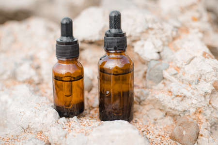 A bottle of cosmetic oil on a background of stones. Cosmetic oil. Cosmetology. Stones. An oil based on algae. Copy spaceの写真素材