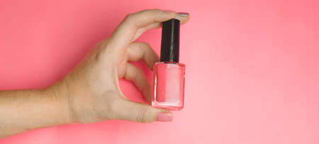 Nail polish in a woman's hand copy space. Article about manicure. Gel polish. Hand care. Pink backgroundの写真素材
