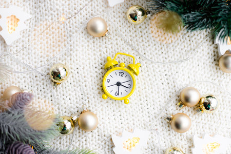Alarm clock on a plaid with a garland. Yellow alarm clock. Cozy vibes. Home comfort. New Year and...