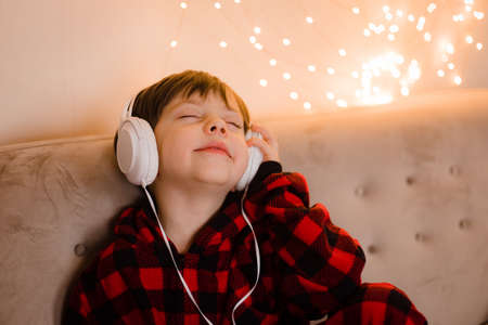 A boy with headphones is lying on the sofa lifestyle. The boy listens to music.の写真素材