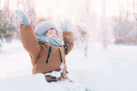 The boy throws snow in winter lifestyle. Winter walks. An article about children's winter leisure. Entertainmentsの写真素材