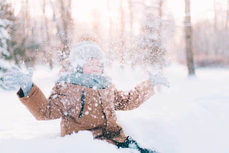 The boy throws snow in winter lifestyle. Winter walks. An article about children's winter leisure. Entertainmentsの写真素材