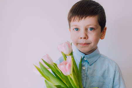 A boy with a bouquet of tulips lifestyle . Postcard for March 8. Congratulations on Womens Day. Congratulations on Mothers Day. Flowers are tulips.の写真素材