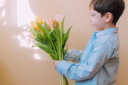 A boy with a bouquet of tulips lifestyle . Postcard for March 8. Congratulations on Womens Day....