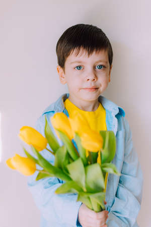 A boy with a bouquet of tulips lifestyle. Postcard for March 8. Congratulations on Women's Day. Congratulations on Mother's Day. Flowers are tulips. baby and flowersの写真素材