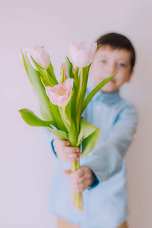 A boy with a bouquet of tulips lifestyle. Postcard for March 8. Congratulations on Women's Day. Congratulations on Mother's Day. Flowers are tulips. baby and flowersの写真素材