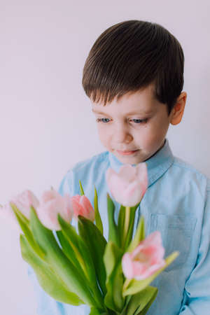 A boy with a bouquet of tulips lifestyle. Postcard for March 8. Congratulations on Women's Day. Congratulations on Mother's Day. Flowers are tulips. baby and flowersの写真素材