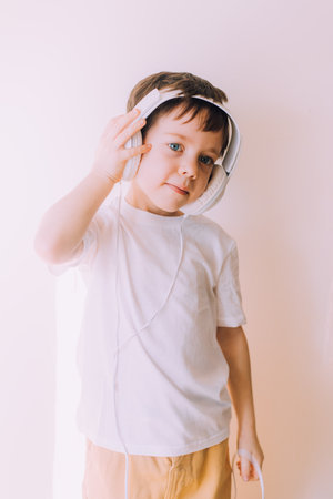 The boy listens to music with lifestyle headphones . Modern technologies. Kids and gadgets. Music for children. Modern children. Smartphones in children.の写真素材