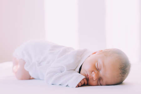 The lifestyle of a sleeping newborn baby on a white background. A sweet childhood dream. An article...