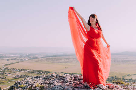 A girl in a red dress on the background of the mountains lifestyle. Illustrating articles about travel. A girl with a beautiful view. Vacation in Crimea. white rock. View of the villages. lifestyle processing. copyspace.の写真素材