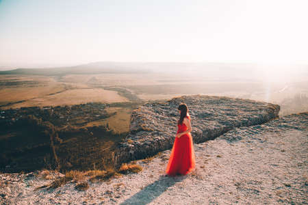 A girl in a red dress on the background of the mountains lifestyle. Illustrating articles about travel. A girl with a beautiful view. Vacation in Crimea. white rock. View of the villages. lifestyle processing. copyspace.の写真素材